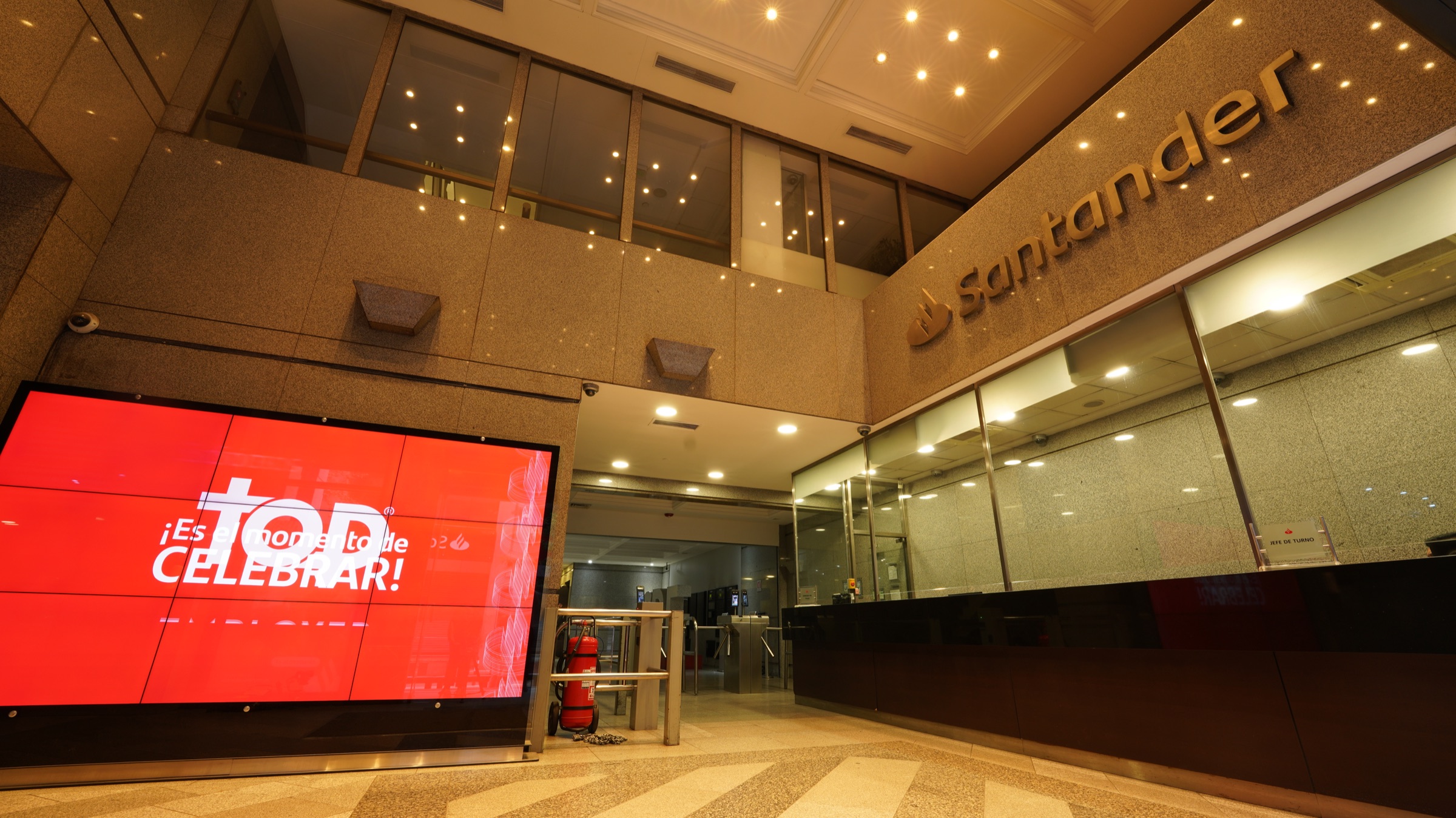 Lobby Santander con pantalla roja y acceso institucional